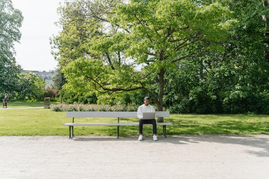 A Man Sitting on a Bench while using a Laptop