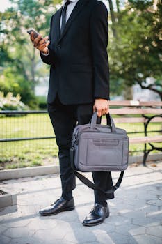 A Person With a Black Suit Using His Phone in The Park