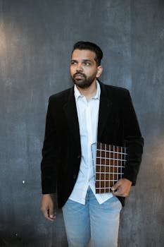 Man in Black Suit Jacket Standing Near Black Wall