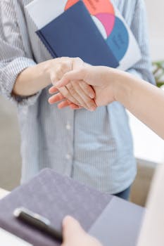 Person in Blue Striped Long Sleeve Shirt Hand Shaking