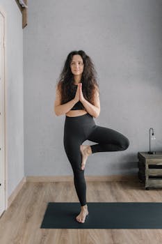 Woman in Black Tank Top and Black Leggings Sitting on Brown Wooden Staircase